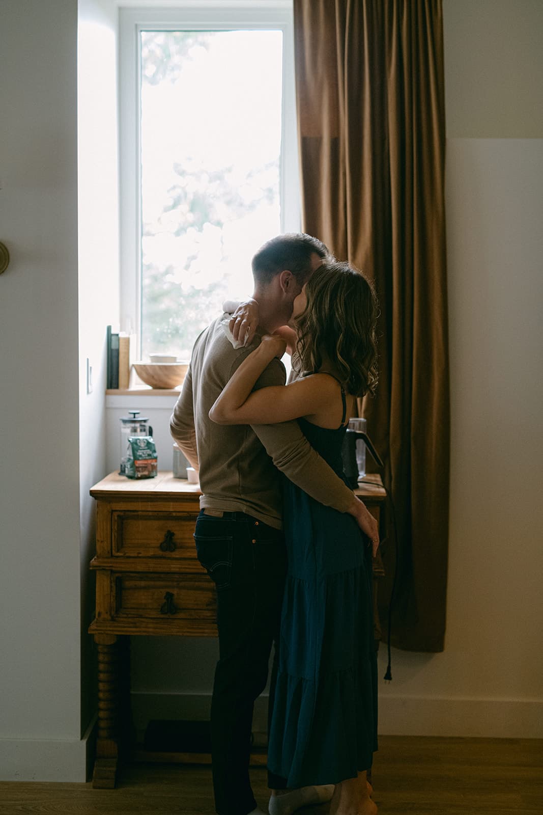 Adam and Emily embrace while waiting for coffee.